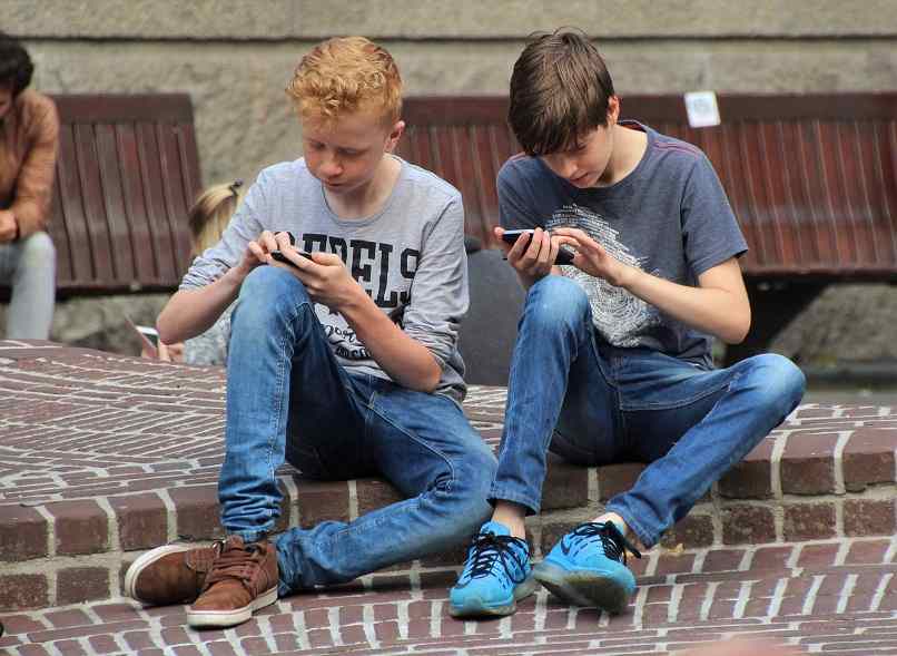 boy playing with mobile phone on the street