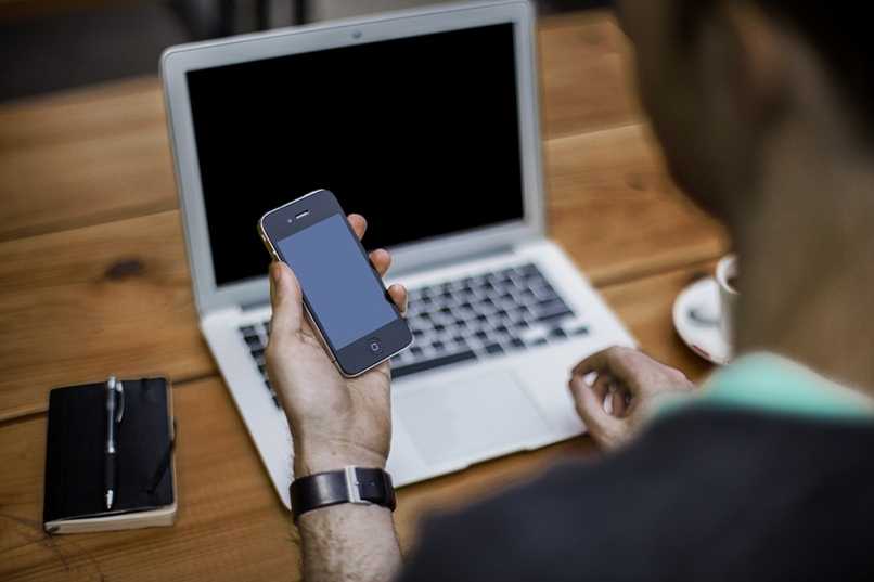 Man configuring mobile phone and pc