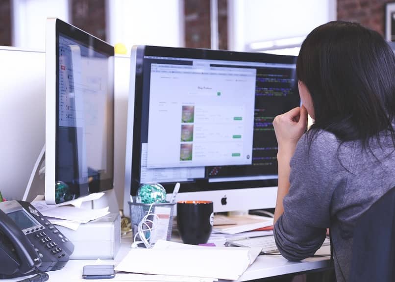 woman looking at two computers