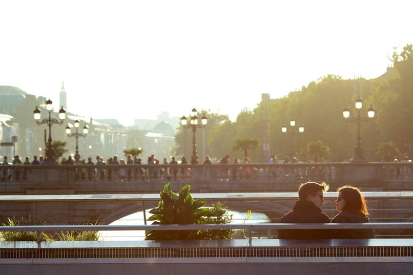 A couple sitting on a bench with a park in the background