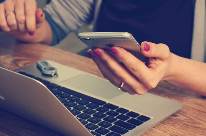 woman looking at phone and computer