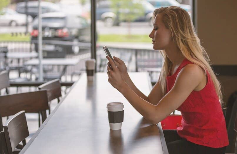 Woman checking mobile phone in cafeteria