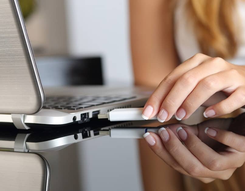 woman putting flash drive into laptop